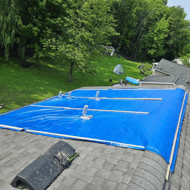 a blue emergency roof tarp placed over asphalt shingle roof during emergency roof repair service